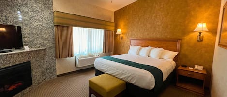 A hotel room with a bed, a television, a heater, a window with curtains, and a nightstand with a lamp.