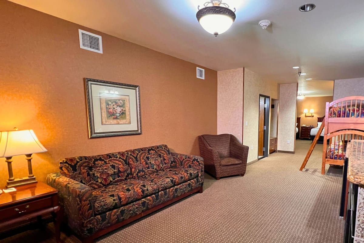 A hotel room with a sofa, armchair, and dining table.