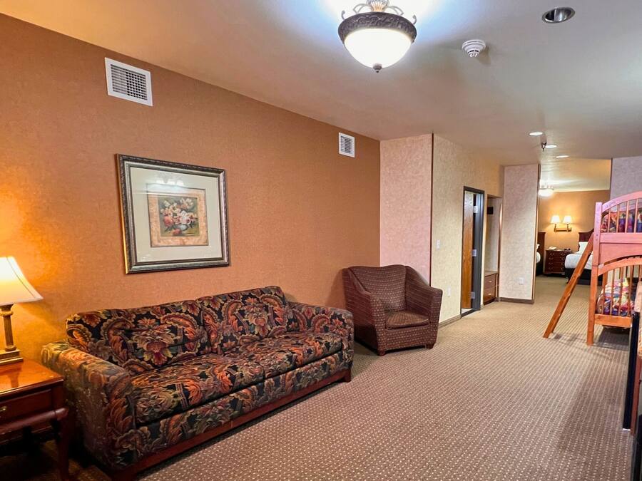 Una habitación de hotel con sofá, sillón y mesa de comedor.