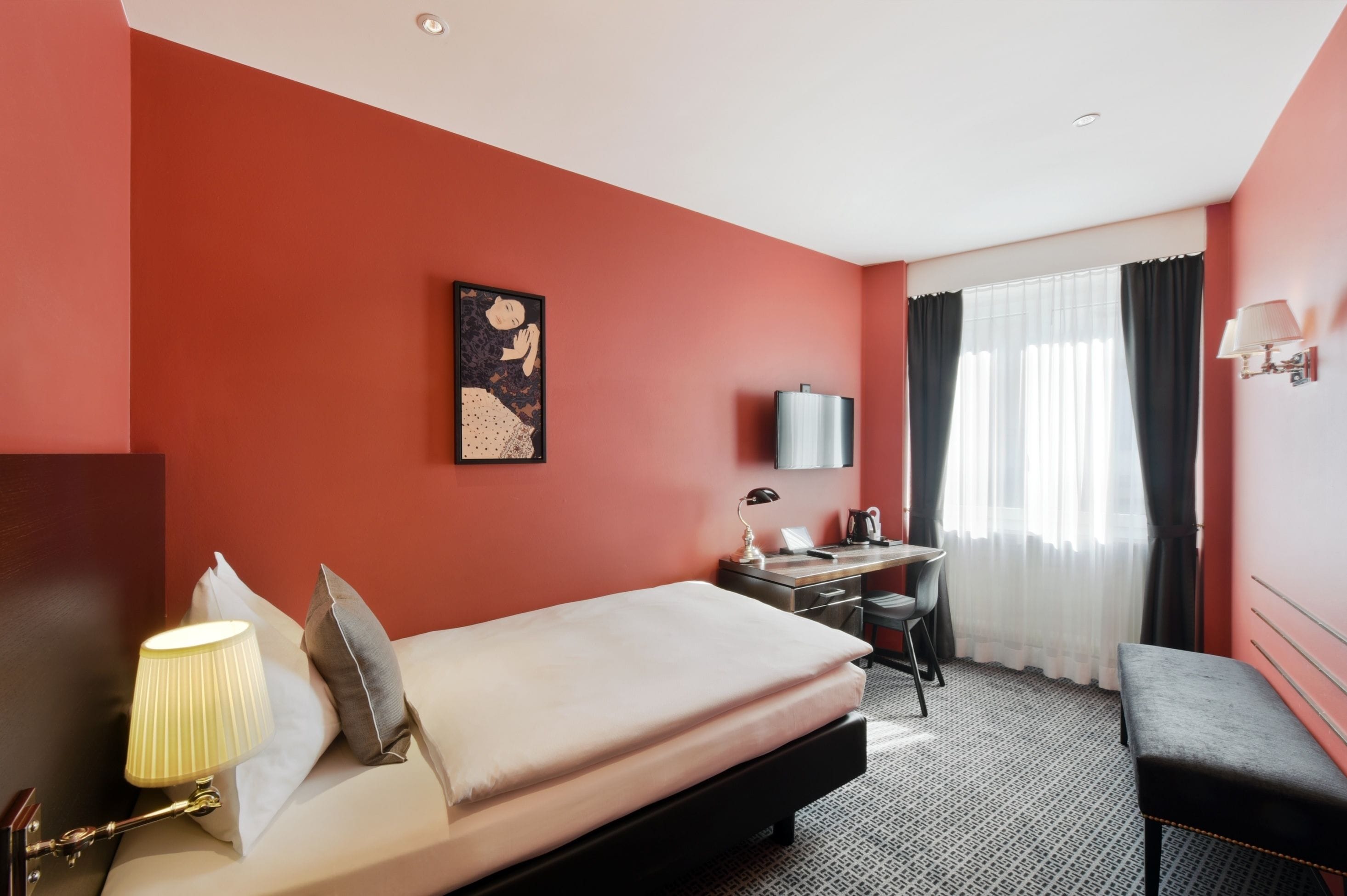 Ein Hotelzimmer mit Bett, Schreibtisch, Stuhl und Fernseher.