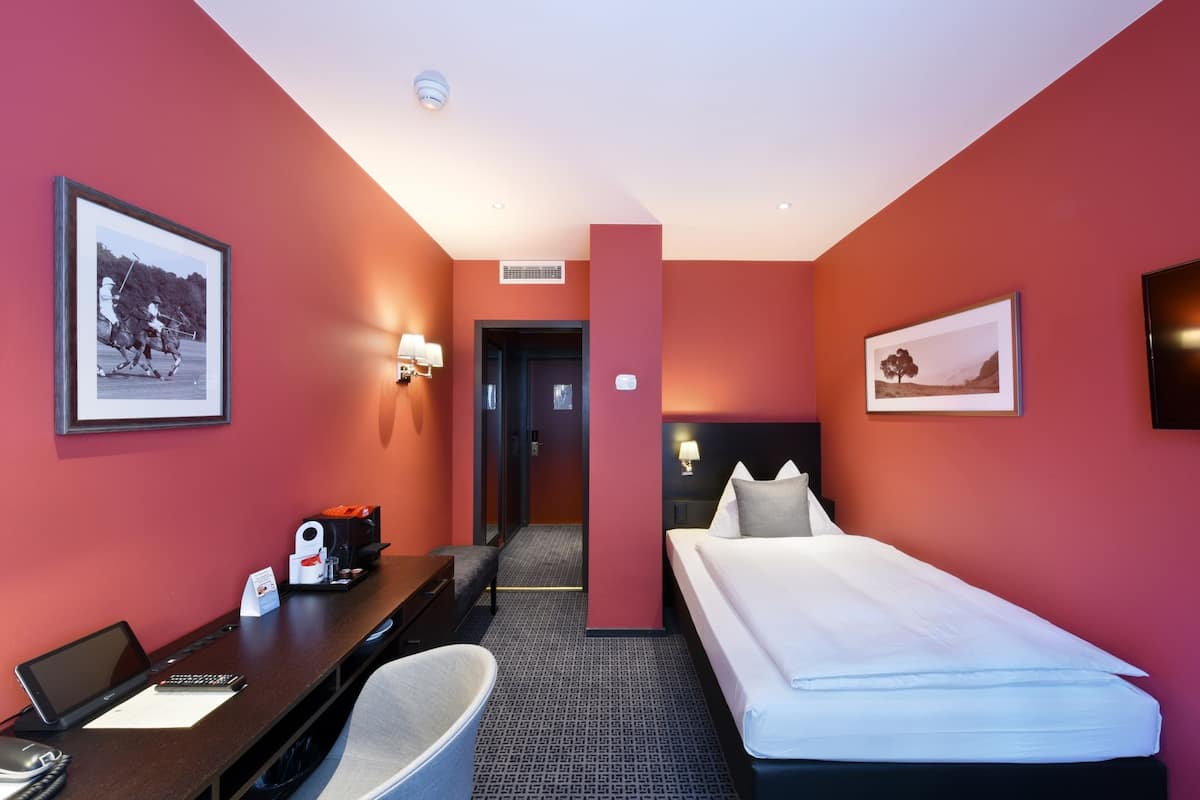 Una habitación de hotel con cama, escritorio, silla y una mesita con cafetera.