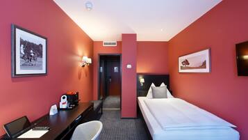 Una habitación de hotel con cama, escritorio, silla y una mesita con cafetera.