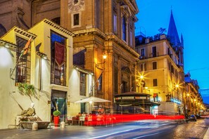 A historic building with a clock tower, outdoor seating, and a tram. - Residenza Canova Tadolini (Rome)