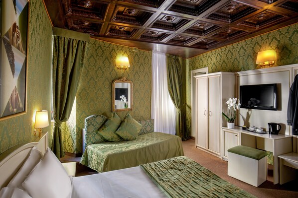 A hotel room with a bed, a desk with a TV, a wardrobe, and a mirror. - Residenza Canova Tadolini (Rome)