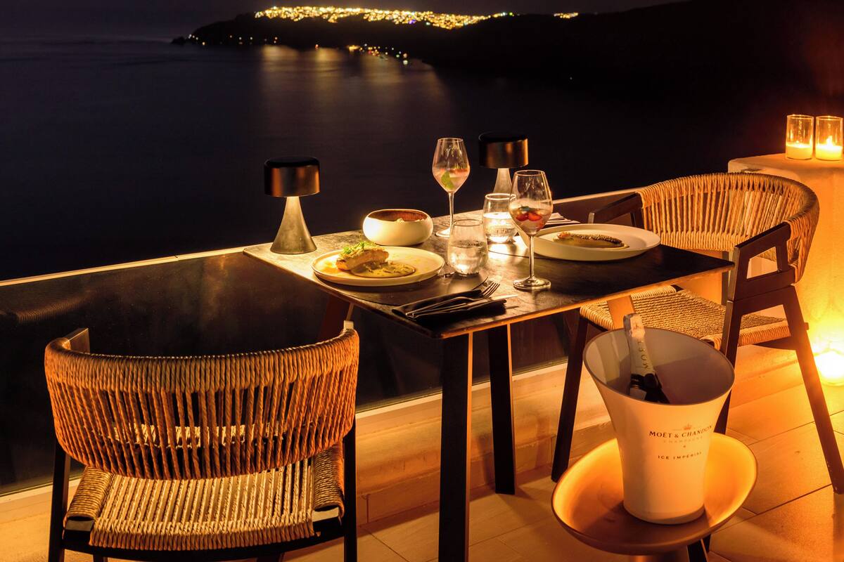 A table set for two with a view of a coastline at dusk.