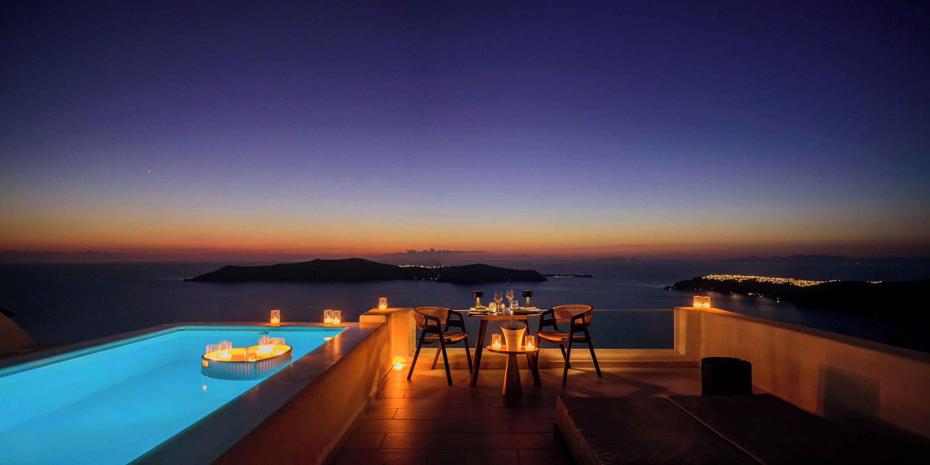 Ein Sonnenuntergangsblick von einer Dachterrasse mit Pool, Esstisch und Stühlen.
