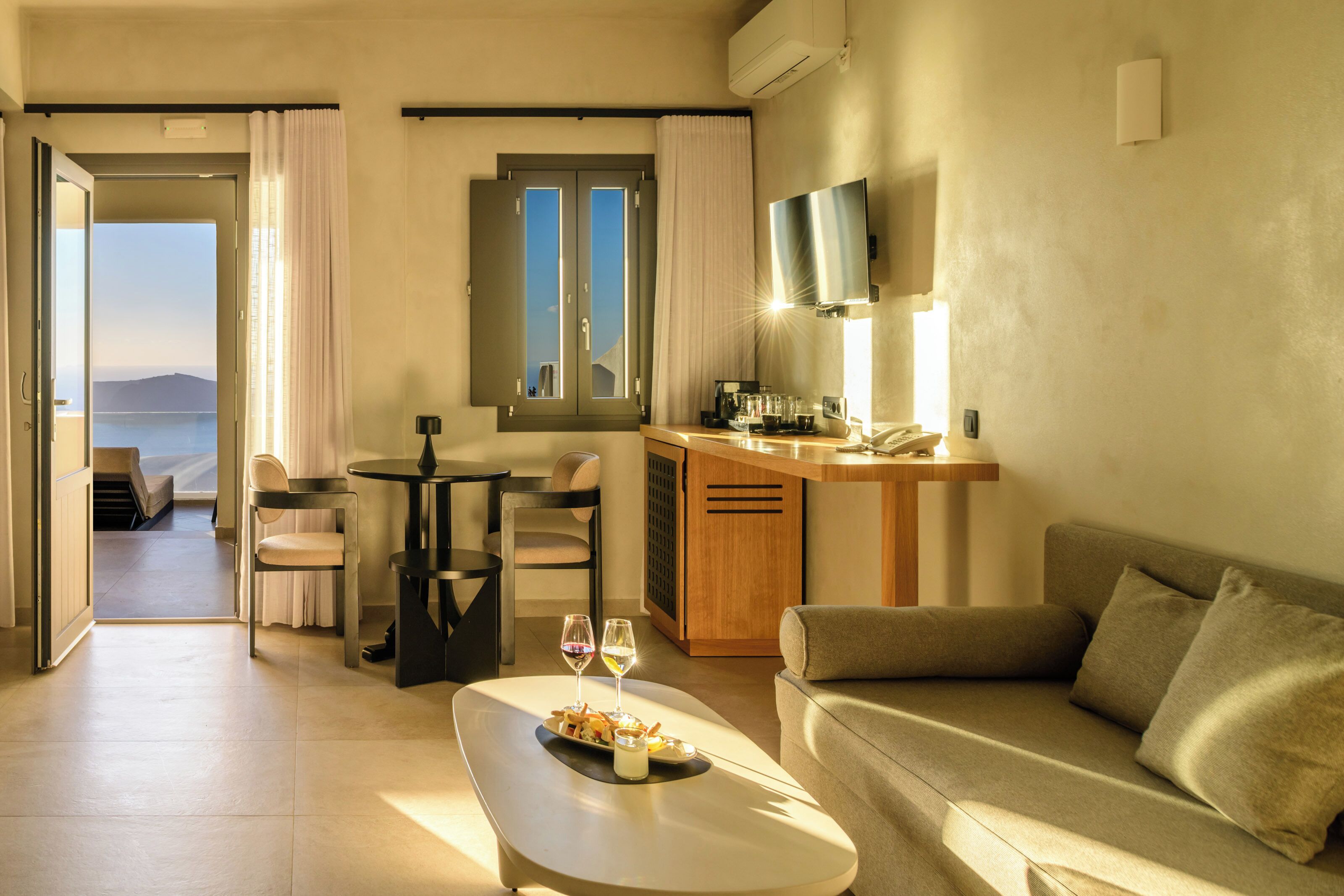 A modern hotel room with a balcony, a dining area, and a sofa.