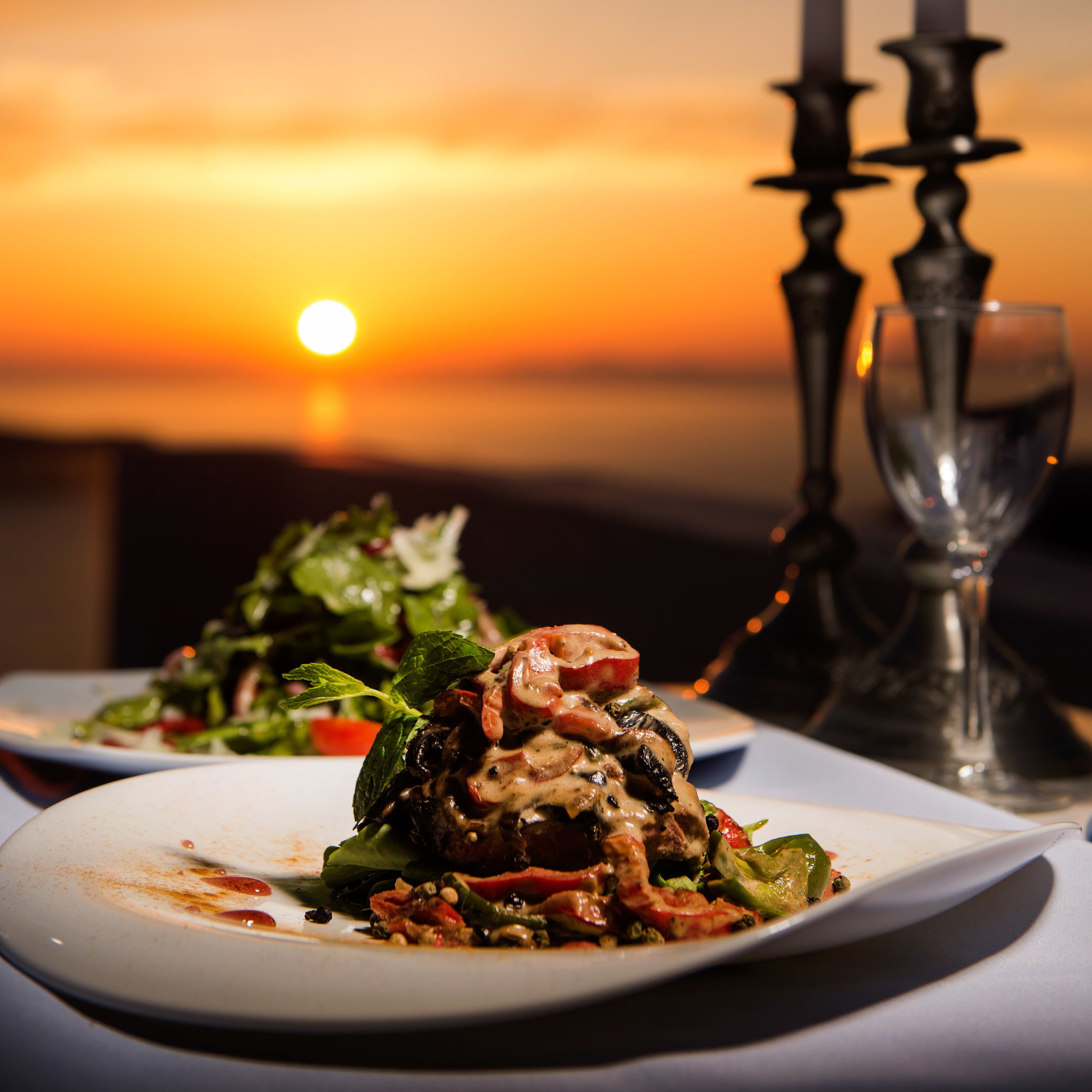 Vista del atardecer con una mesa dispuesta, platos de comida y un candelabro.