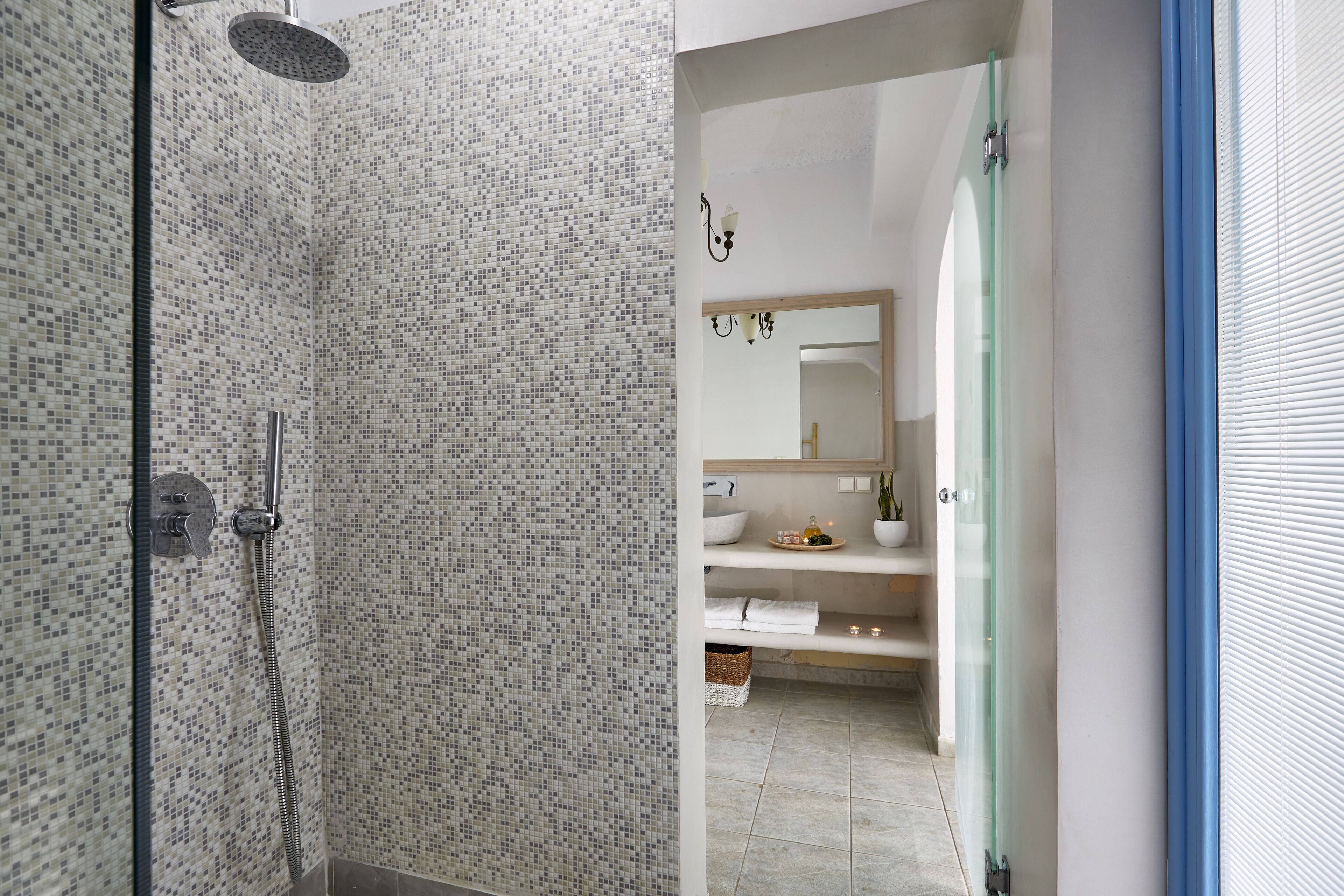 Een badkamer met een douche, wastafel, spiegel en handdoekhouder.