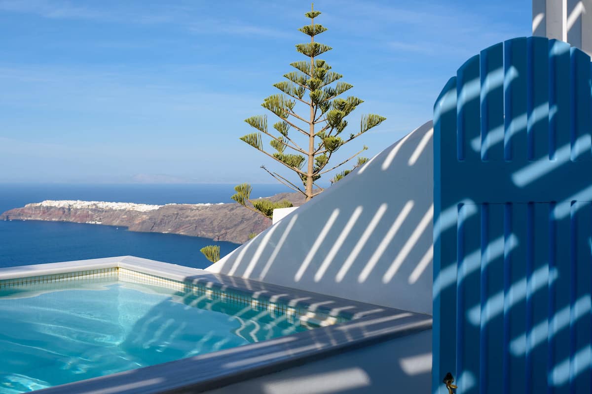 A pool with a view of the sea and a mountainous landscape.