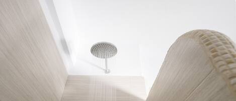 A modern bathroom with a skylight, a showerhead, and a small window with toiletries.