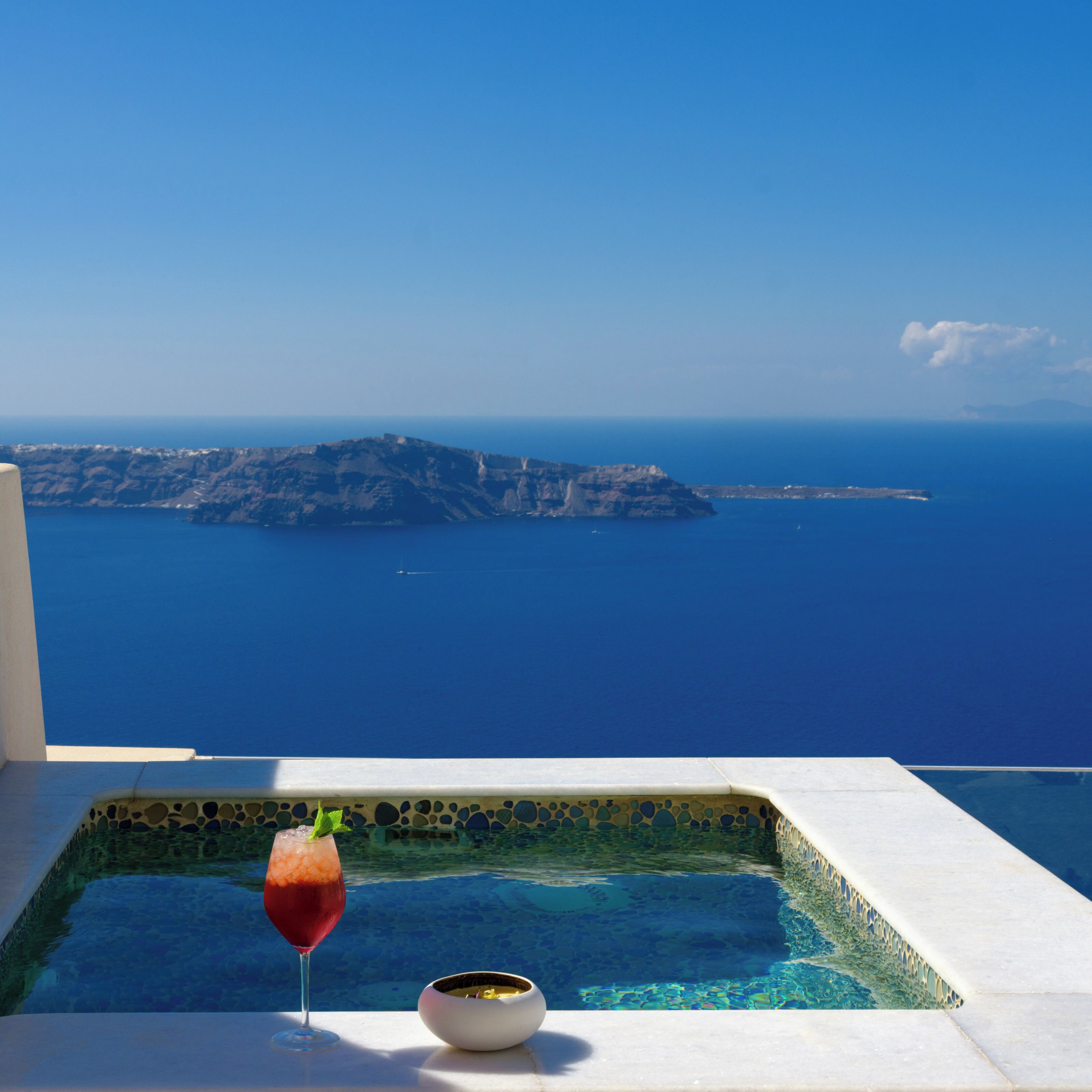 A pool with a clear view of the sea and a distant island.