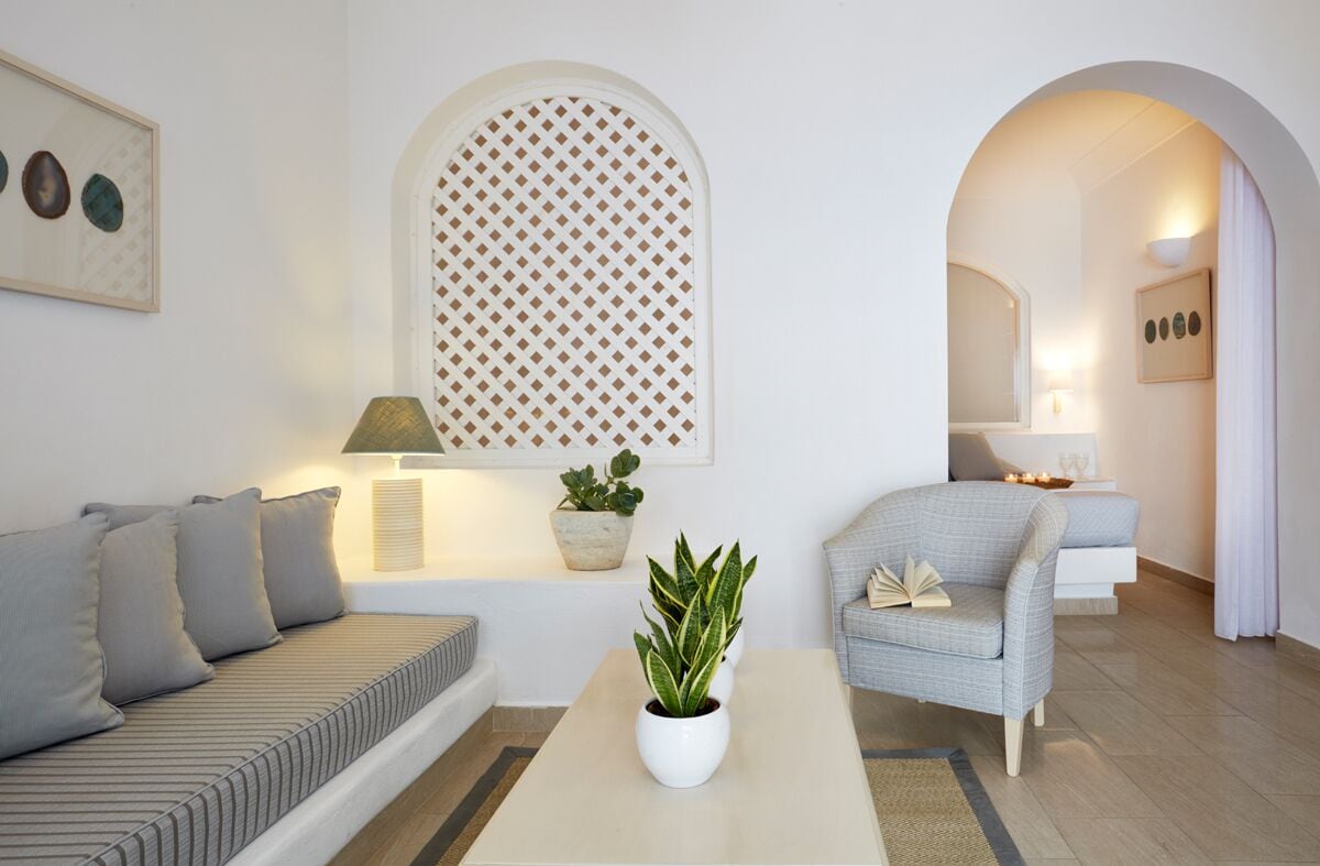 Een moderne woonkamer met een bank, fauteuil, salontafel en potplanten.