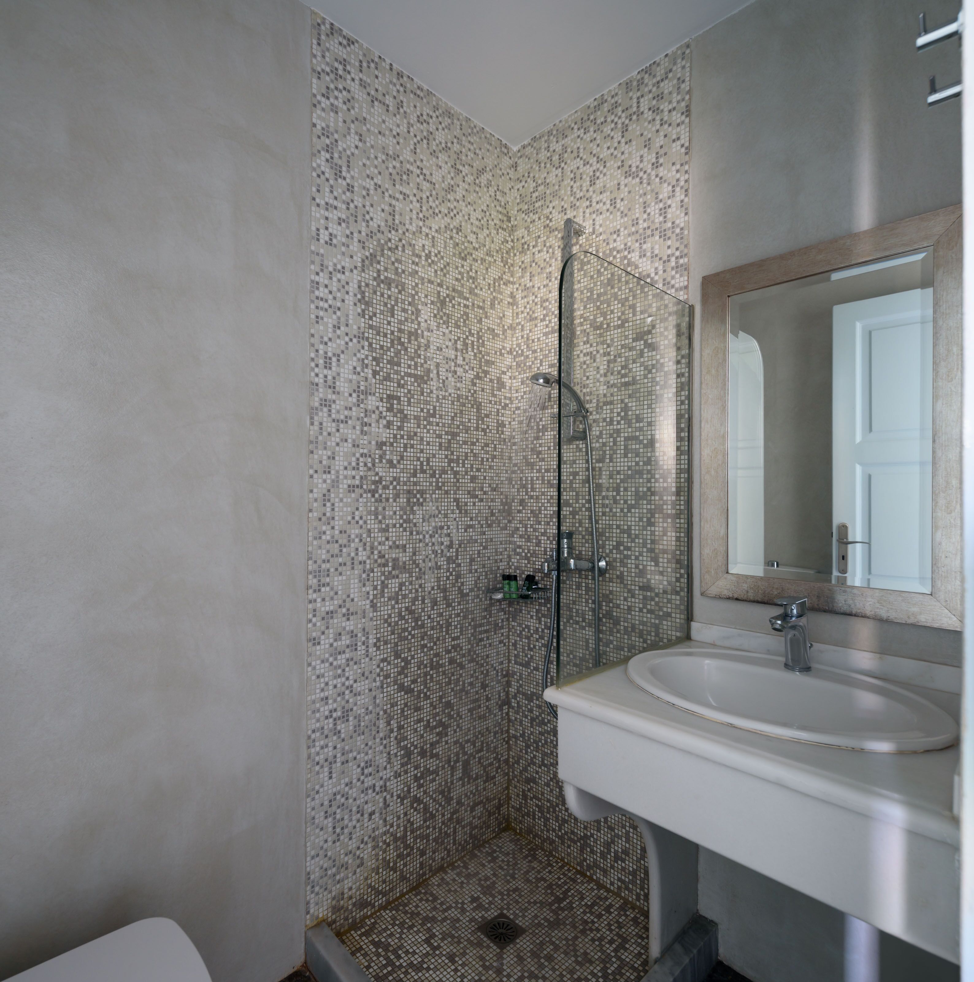Ein Badezimmer mit Dusche, Waschbecken und Spiegel.