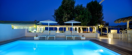 Una piscina al aire libre, sombrillas, sillones reclinables de piscina