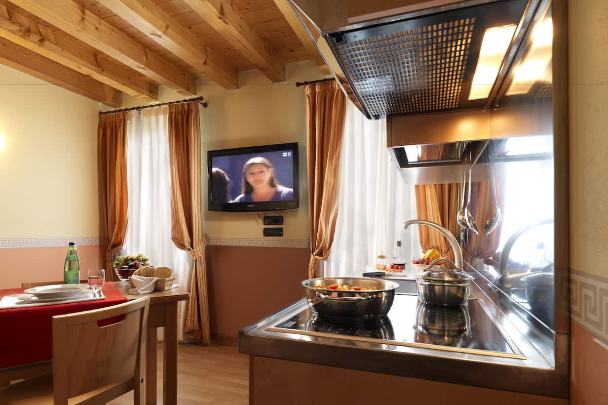 A kitchen with a TV, wooden ceiling, and a dining area with a table and chairs.