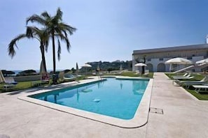 Una piscina al aire libre de temporada, sombrillas