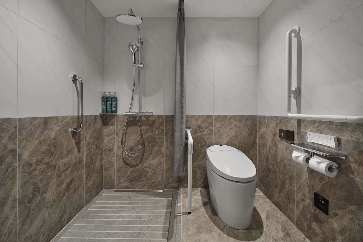 A modern bathroom with a shower, toilet, and hand dryer.