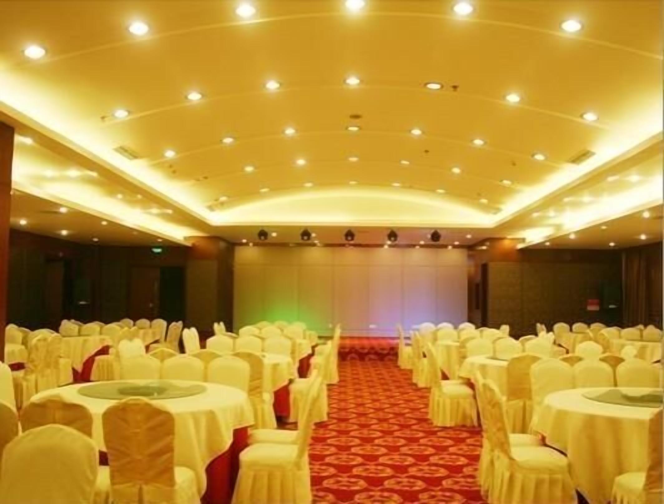 A banquet hall with round tables and chairs, a red carpet, and a stage at the front.