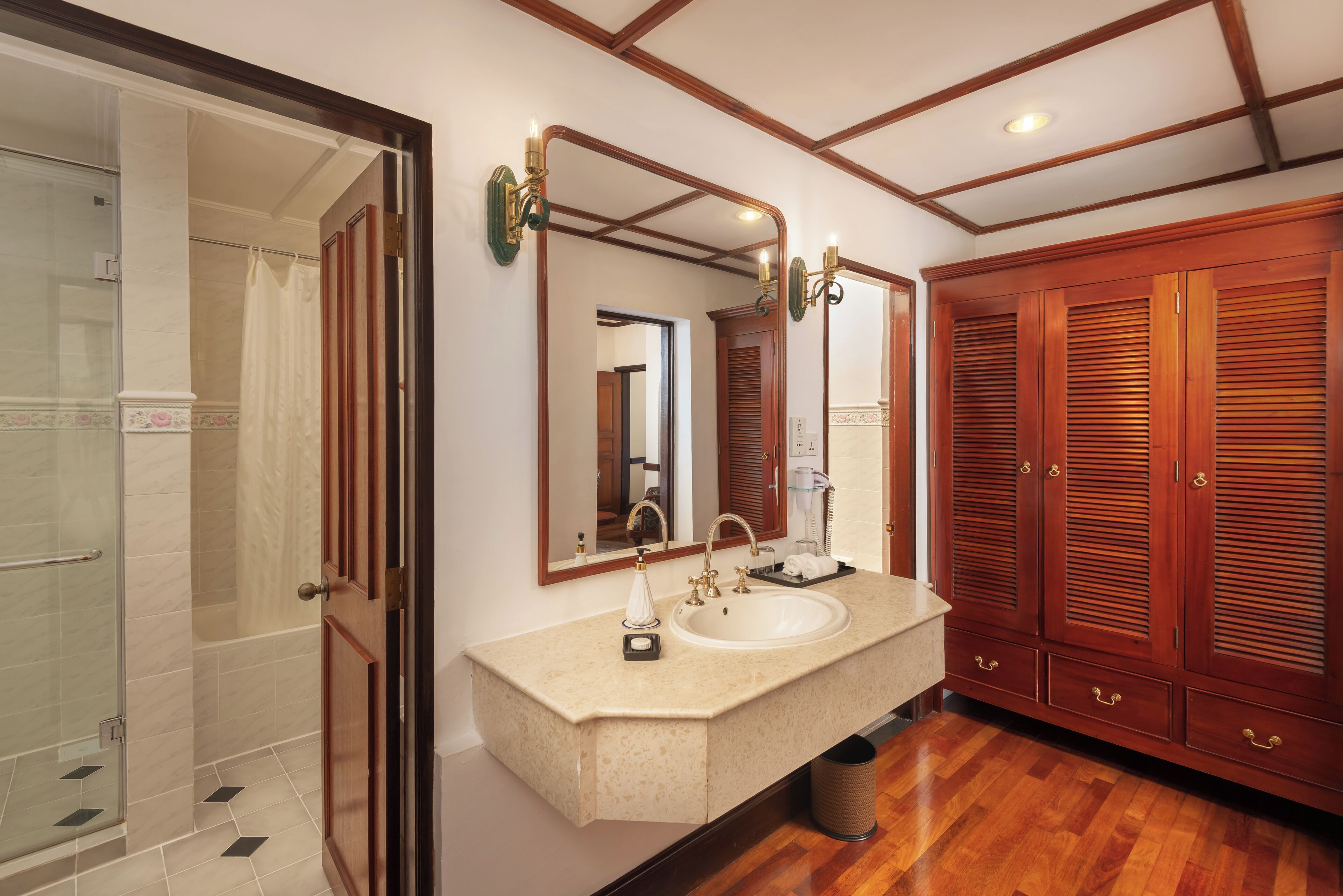 A bathroom with a sink, mirrors, wooden cabinets, and a shower area.