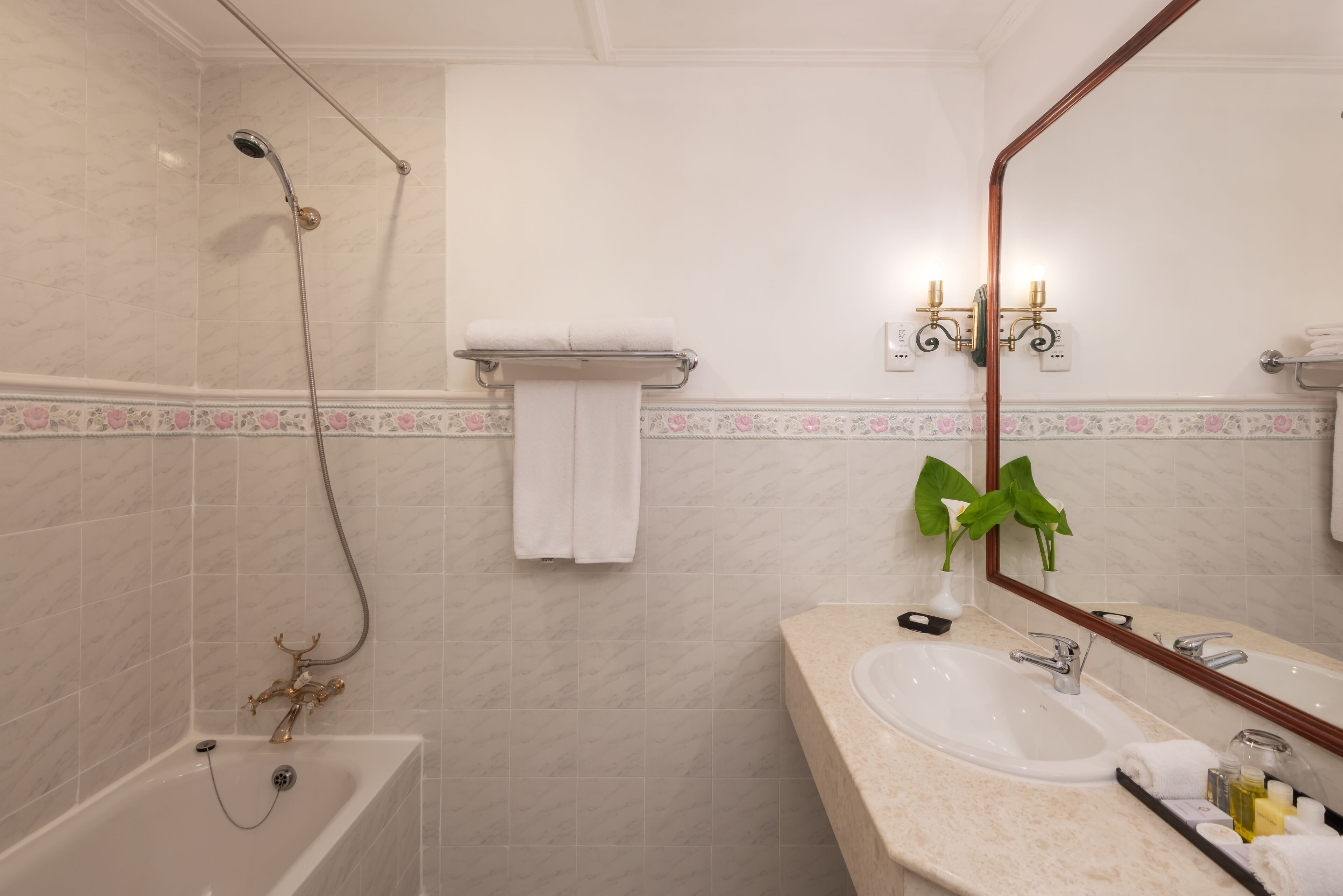 A bathroom with a bathtub, a sink, a mirror, and a towel rack.