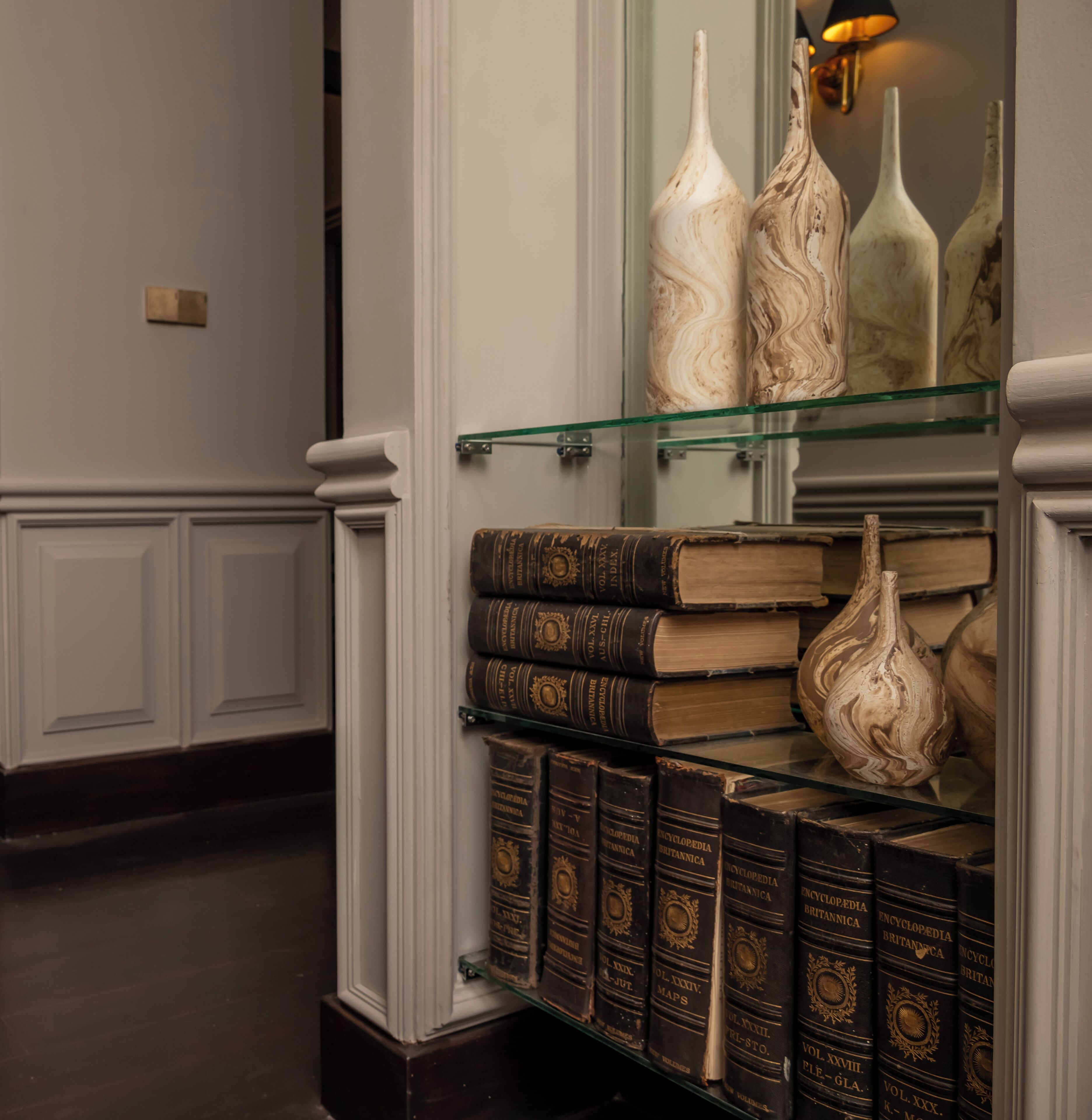 A section of a library with bookshelves, a glass display case, and decorative vases.