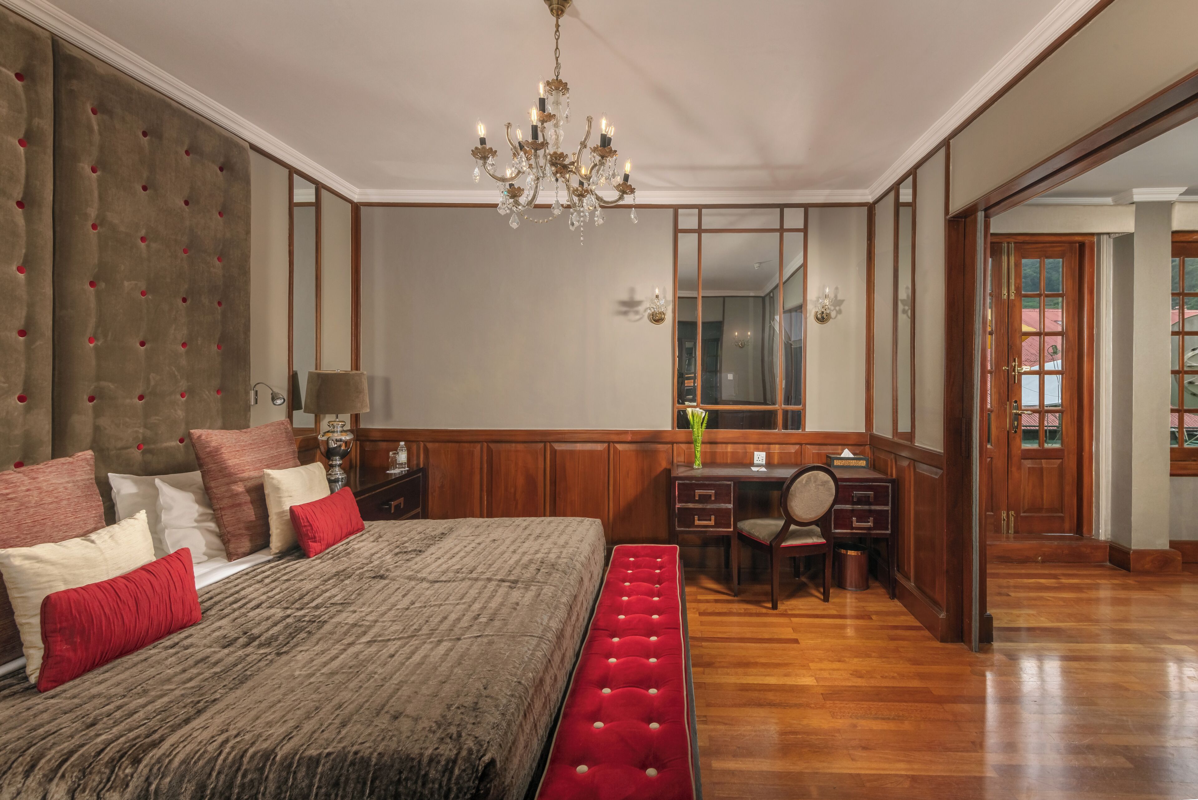A spacious bedroom with a large bed, a wooden desk, and a chandelier.