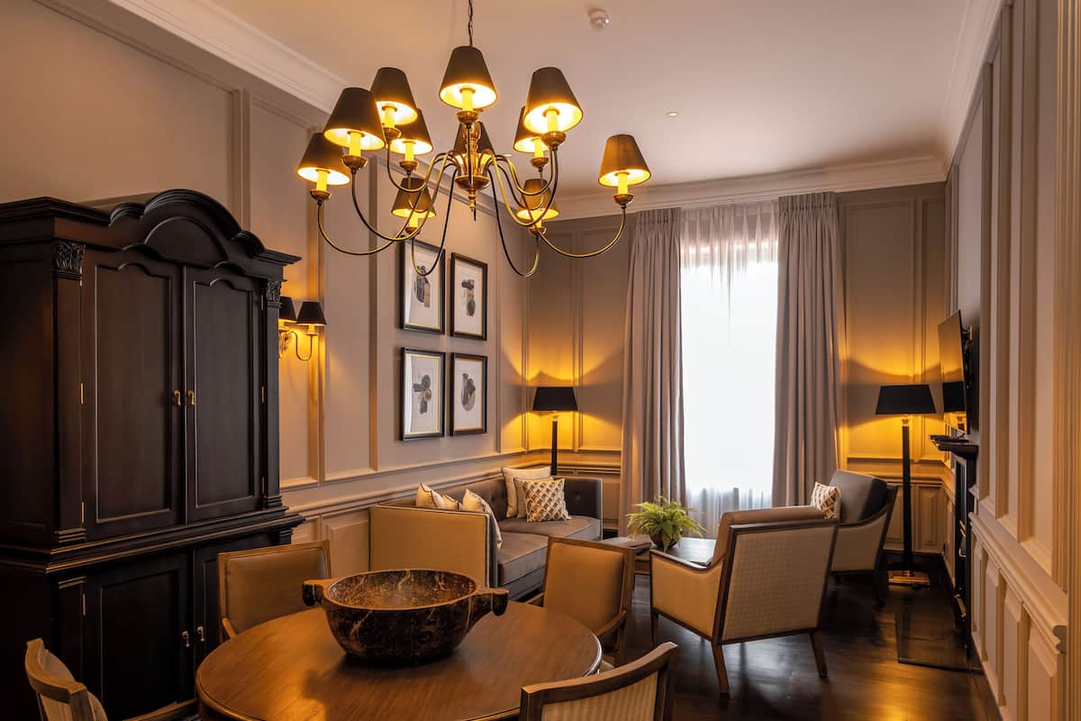 A dining area with a chandelier, dark wooden furniture, and a large bowl on the table.