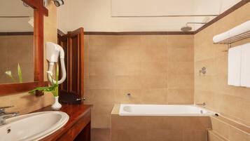 A bathroom with a wooden vanity, a white sink, a large mirror, a shower with a handheld showerhead, and a bathtub.