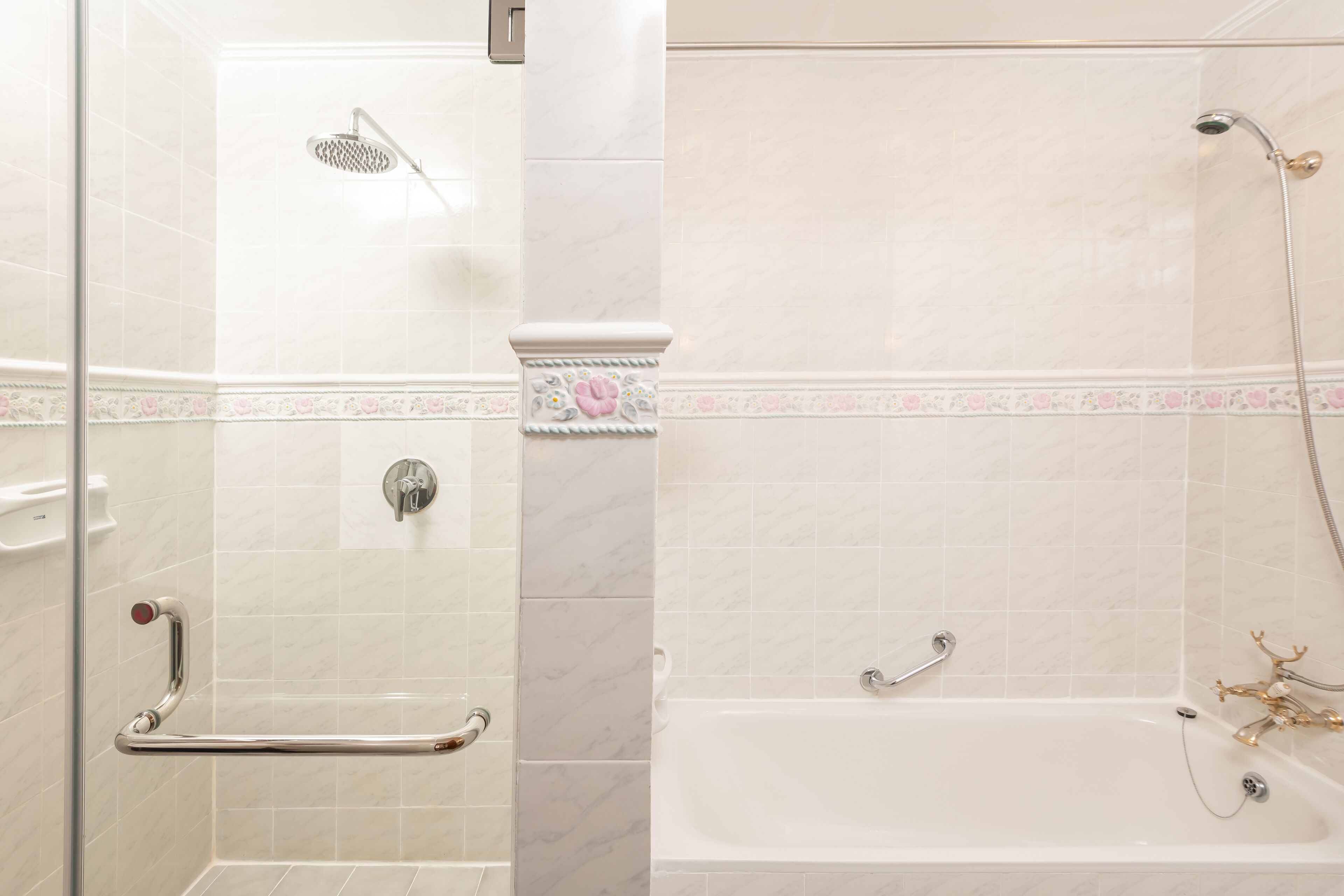A bathroom with a shower, a bathtub, and a handrail.