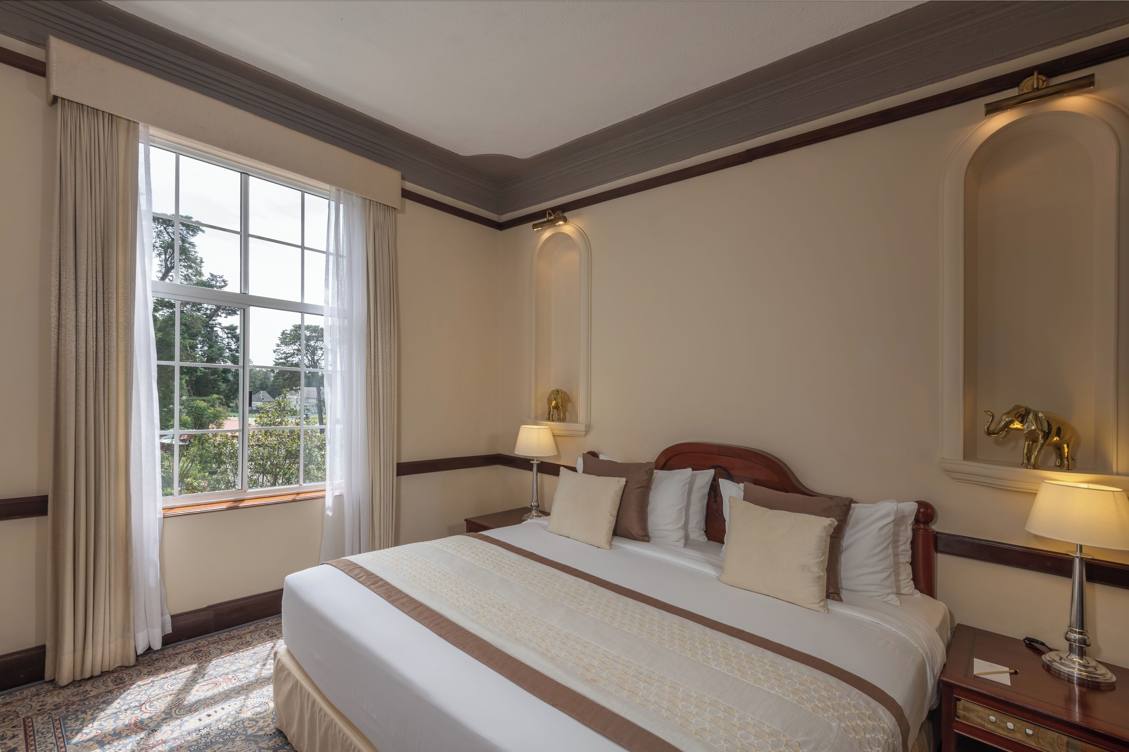 A hotel room with a large bed, two bedside tables, a window with curtains, and a mirror on the wall.