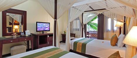 A hotel room with two beds, a desk, a television, and a large window with a view of palm trees.