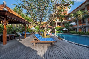 A wooden deck with lounge chairs and a pool. - Adi Dharma Hotel Kuta (Kuta)
