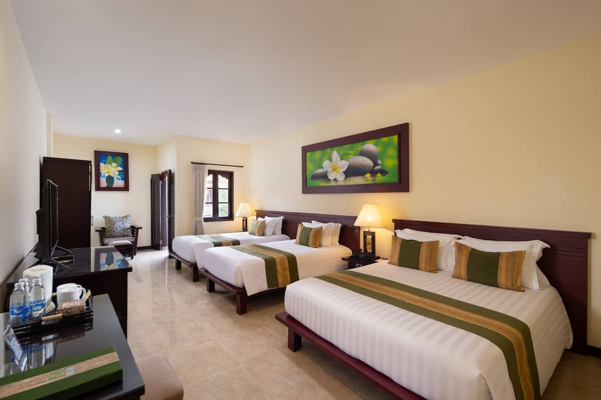 A hotel room with three beds, a desk with a computer, a TV, and a painting on the wall.