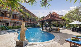 A swimming pool with a statue, lounge chairs, and a gazebo.