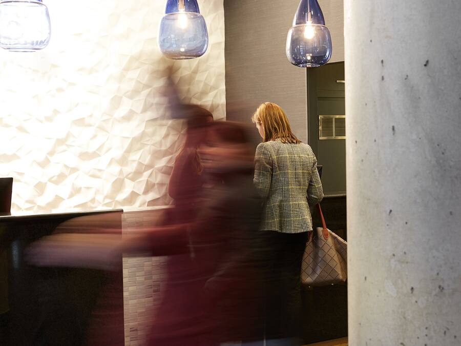 Un vestíbulo con mostrador de recepción, lámparas colgantes y una pared con textura.