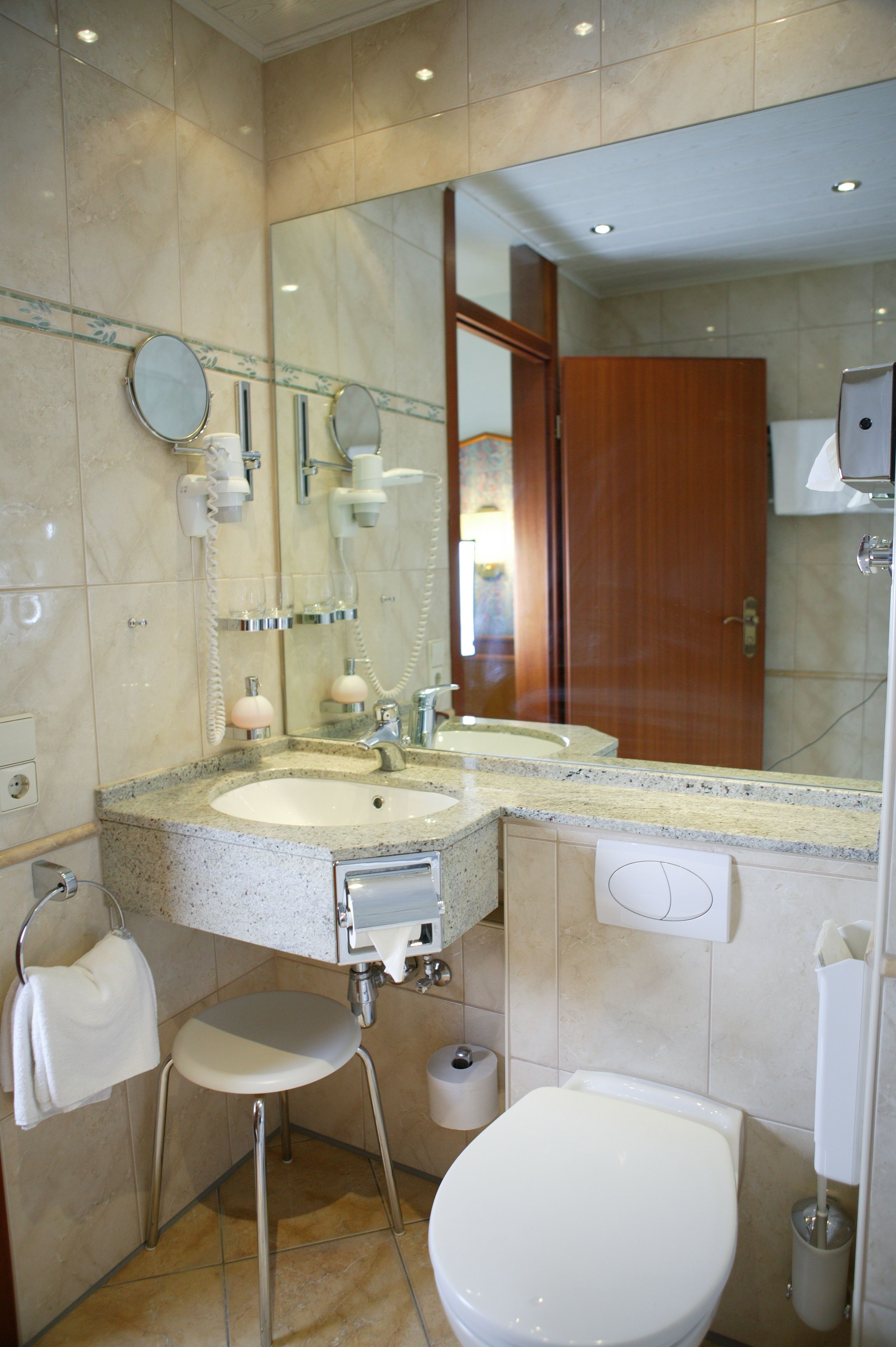 Une salle de bain équipée d’un lavabo, d’un miroir, de toilettes et d’un porte-serviettes.