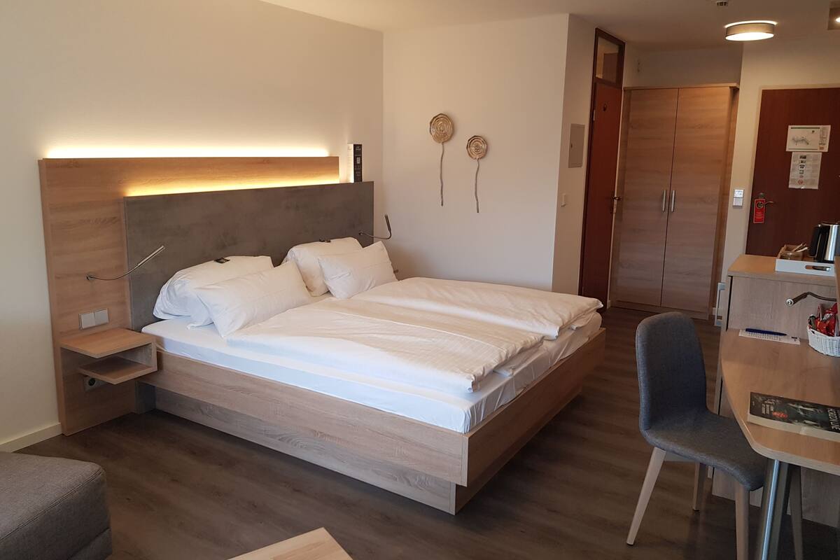 Una habitación de hotel moderna con una cama grande, mesitas de noche, un escritorio y una silla.