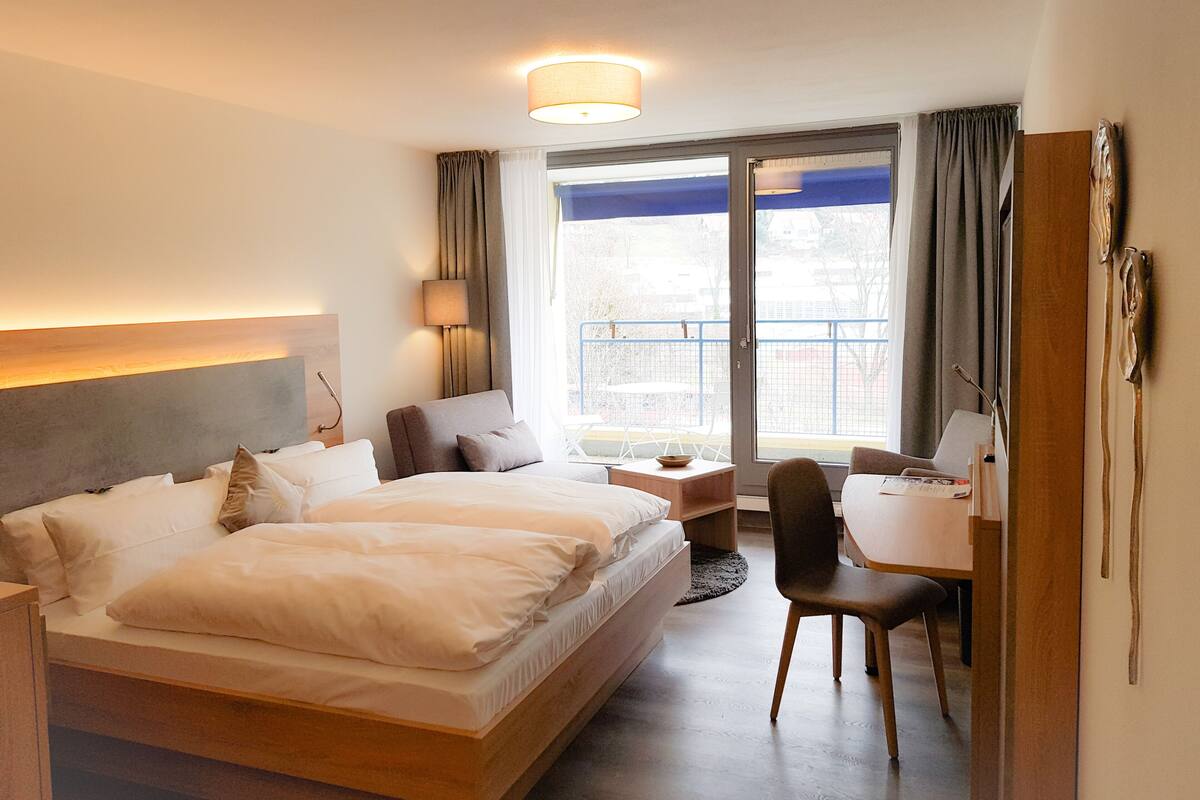 Habitación de hotel con una cama grande, un escritorio y vistas al exterior.