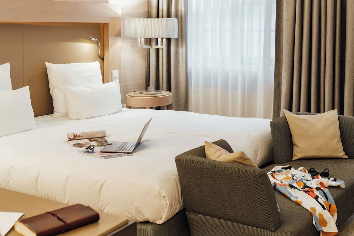 Ein Hotelzimmer mit einem großen Bett, einem Schreibtisch, einem Sessel und einer Couch.