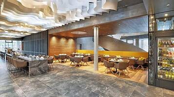 A modern interior with a central seating area, a bar on the right, and a staircase leading to an upper level.