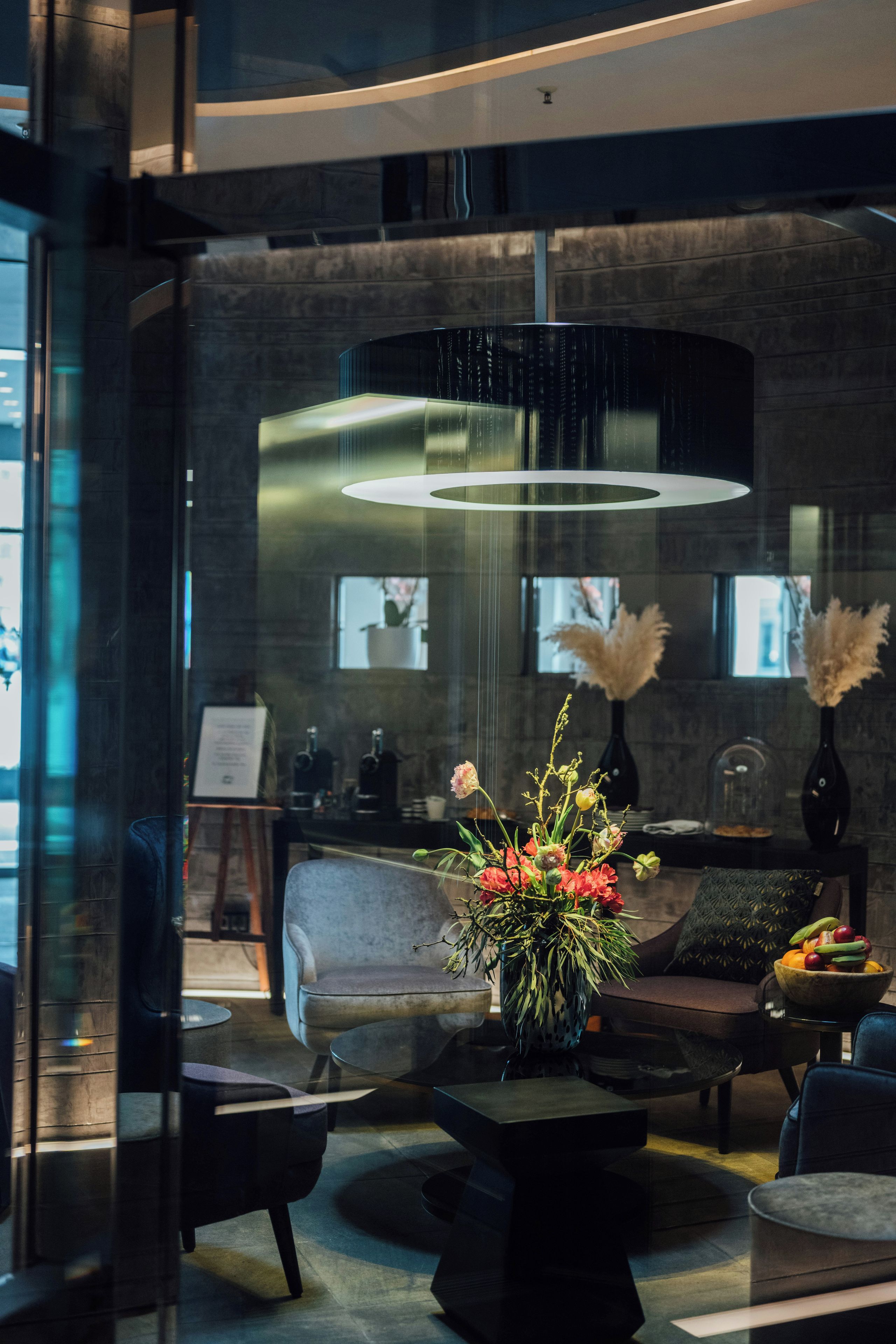 A modern interior with a sofa, a coffee table, and a vase with flowers.