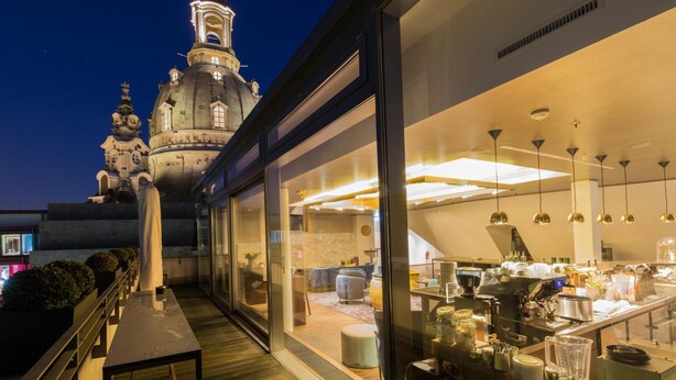 Un hôtel moderne doté d’un espace repas, de grandes fenêtres et offrant une vue sur un bâtiment historique à coupoles.