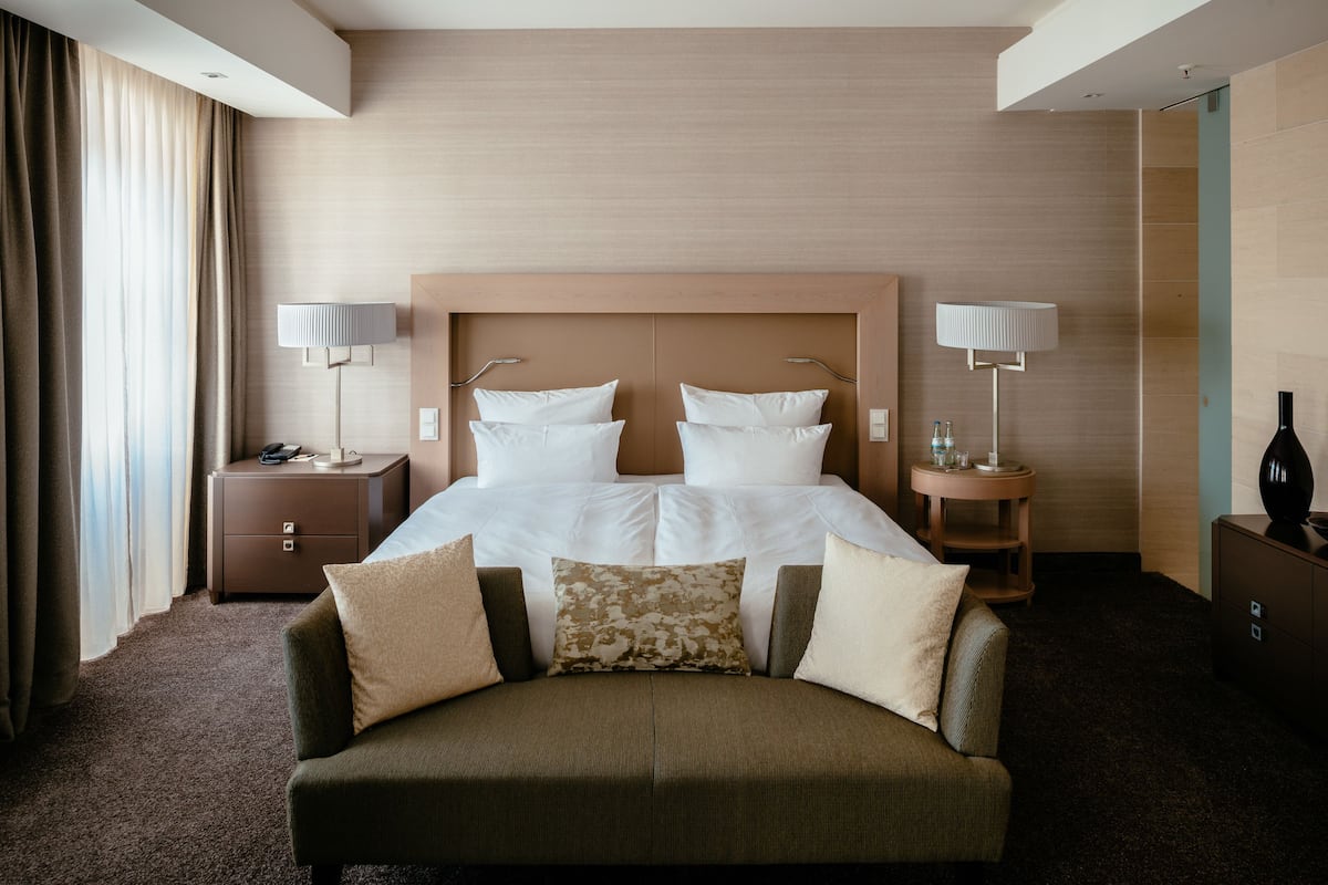 Ein Hotelzimmer mit einem großen Bett, zwei Nachttischen, einem Sofa und einem Spiegel.