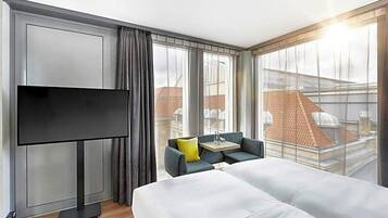 Ein Hotelzimmer mit Bett, Fernseher, kleinem Tisch und einer Couch.