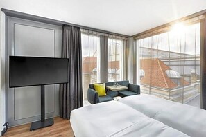 A hotel room with a bed, a TV, a small table, and a sofa. - The Cloud One Dresden-Frauenkirche (Dresden)