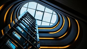 Un bâtiment moderne doté d’un escalier en colimaçon et offrant une vue sur le ciel grâce à une grande fenêtre.