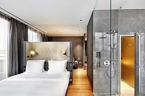 A modern hotel room with a large bed, a shower area, and a view of the city. - The Cloud One Dresden-Frauenkirche (Dresden)