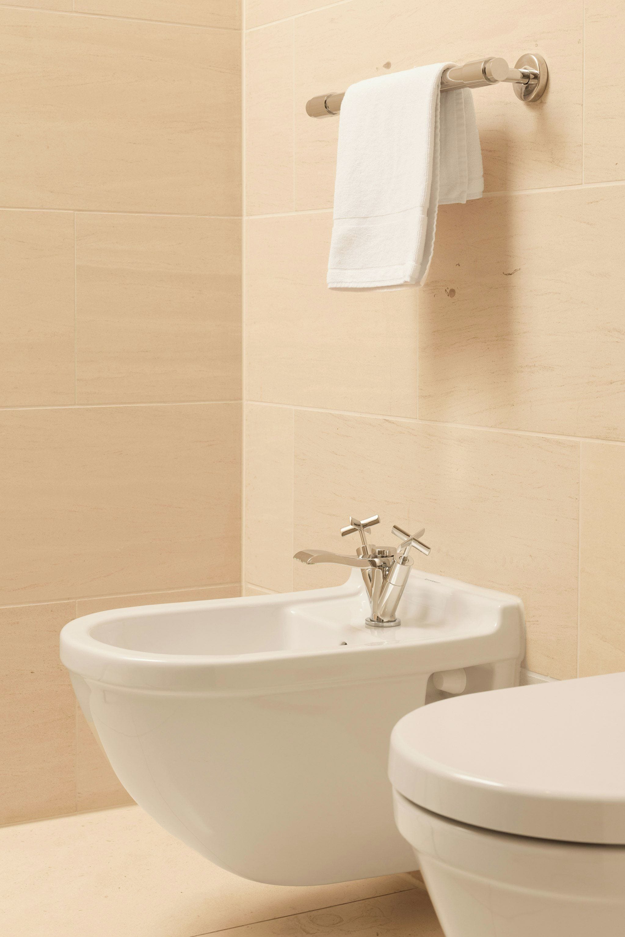 A bathroom with a white sink, a toilet, and a towel rack with a white towel.