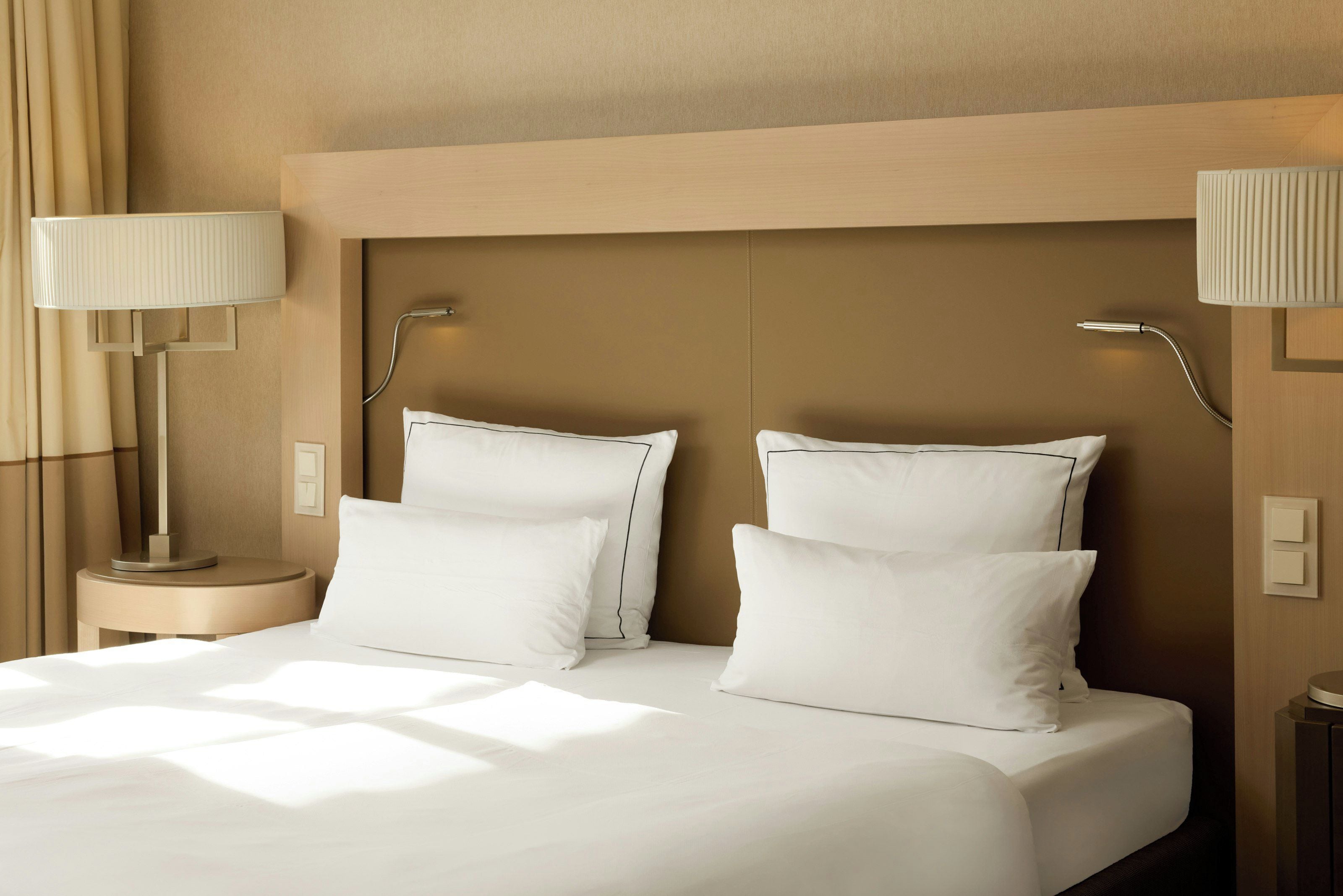 Ein Hotelzimmer mit einem großen Bett, zwei Nachttischlampen und einem Kopfteil.